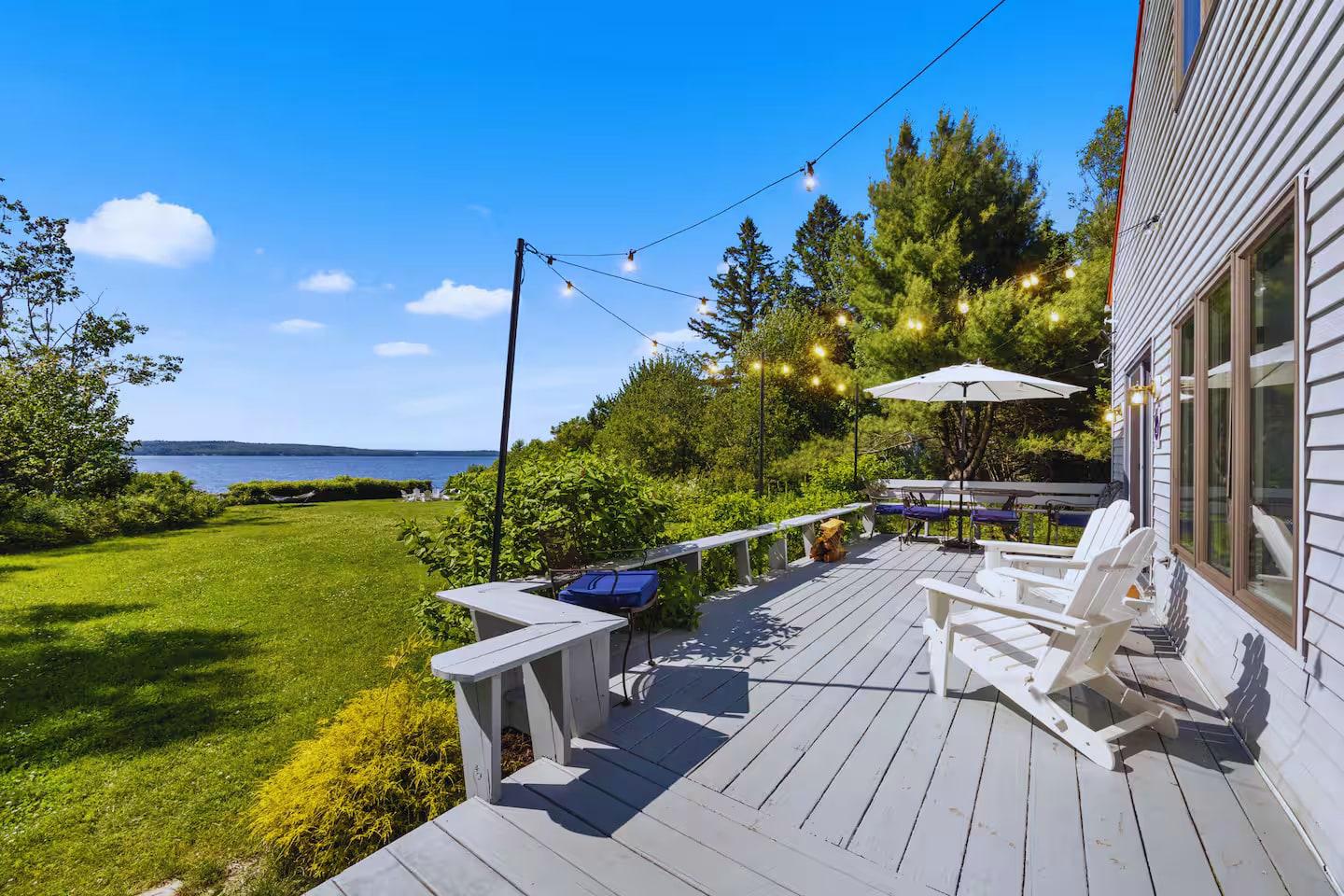 Deck with string lights and an umbrella overlooking the bay on a summer evening at Eagles Nest