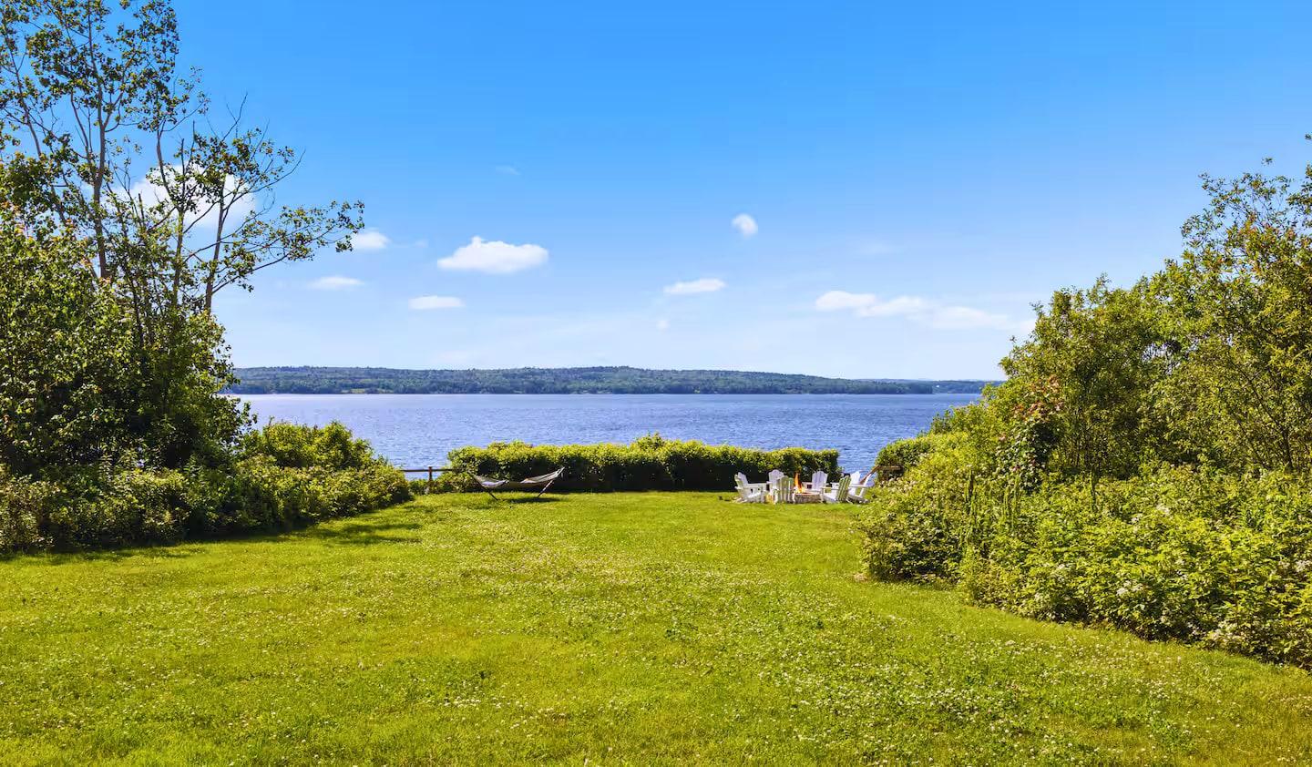 The private summer lawn running down to the bay, hammock and fire-pit chairs, at Eagles Nest