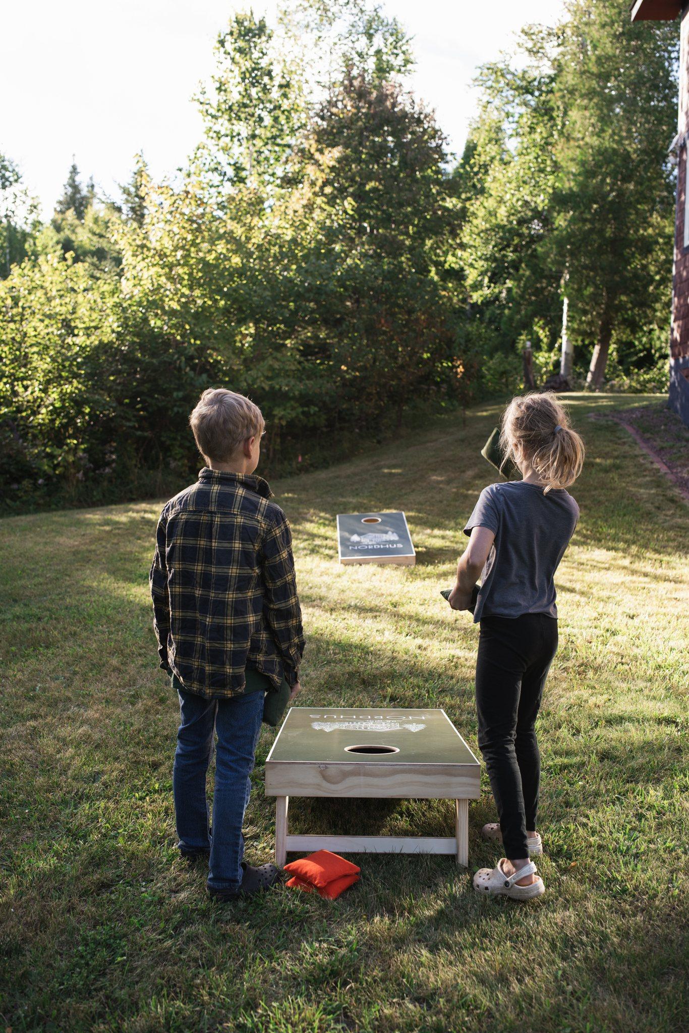 Children playing cornhole on the lawn in evening light at Nordhus Lodge